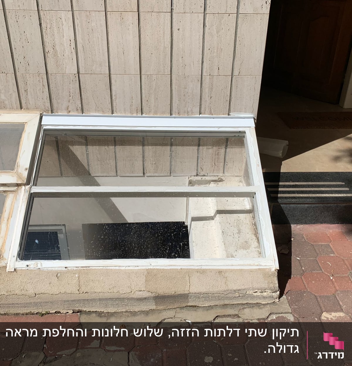 חלון זכוכית משופע עם מסגרת לבנה על קיר חיצוני